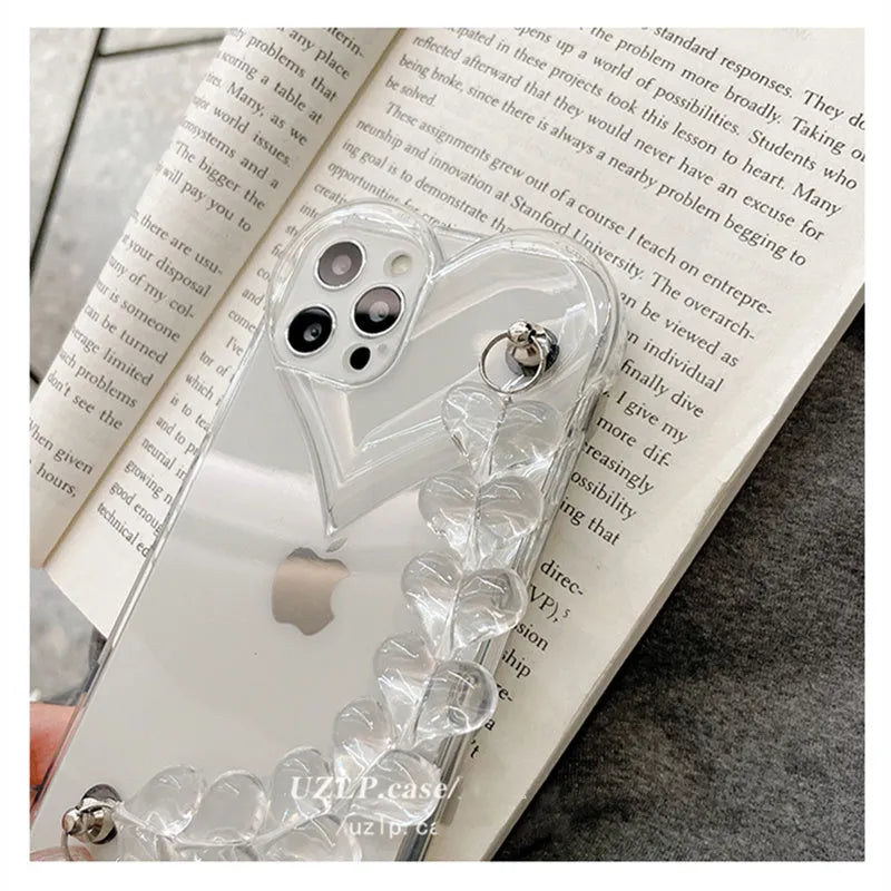 Transparent soft TPU iPhone case with a built-in clear love heart charm and chain.