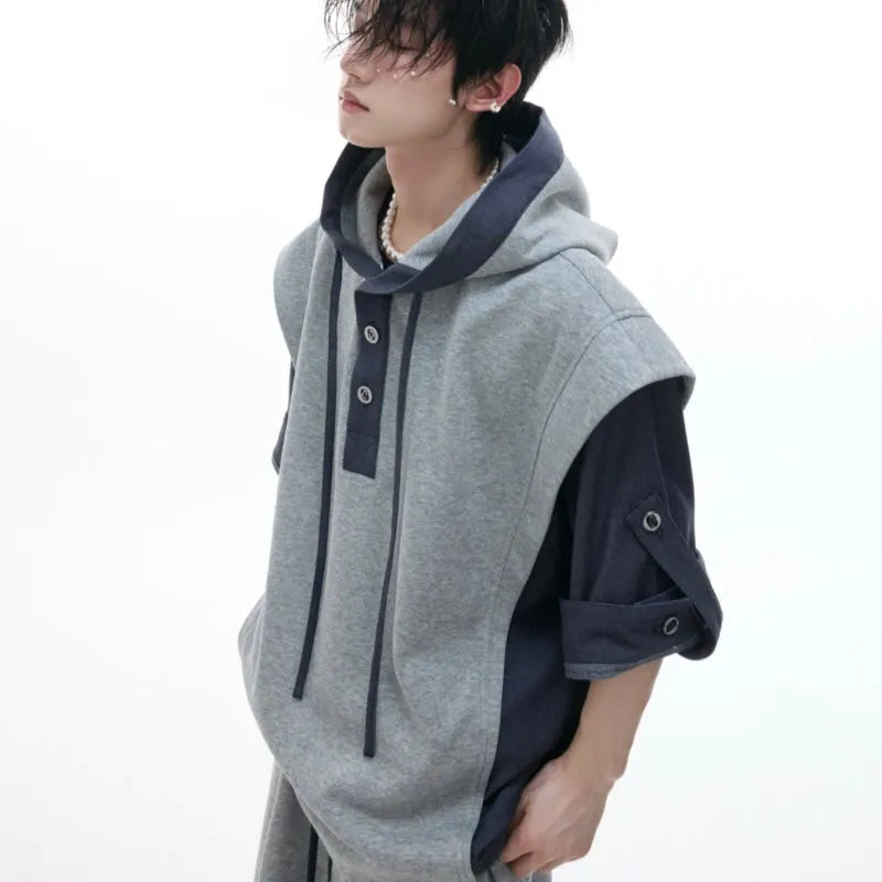 Man wearing a grey hooded short-sleeve sweatshirt and matching trousers with three-dimensional stitching detail.