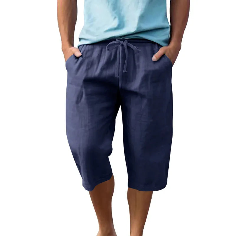 Man wearing loose, high-waisted linen shorts in a solid colour with a drawstring waist.