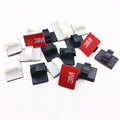 Black and white plastic self-adhesive cable clamps for car wire management on a clean surface.