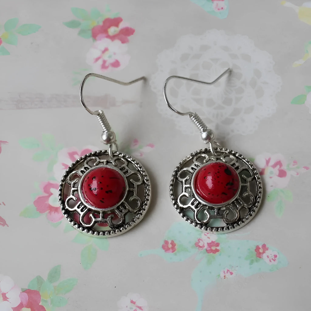 Handmade Miao silver retro earrings with turquoise flower disk and ethnic patterns in black.
