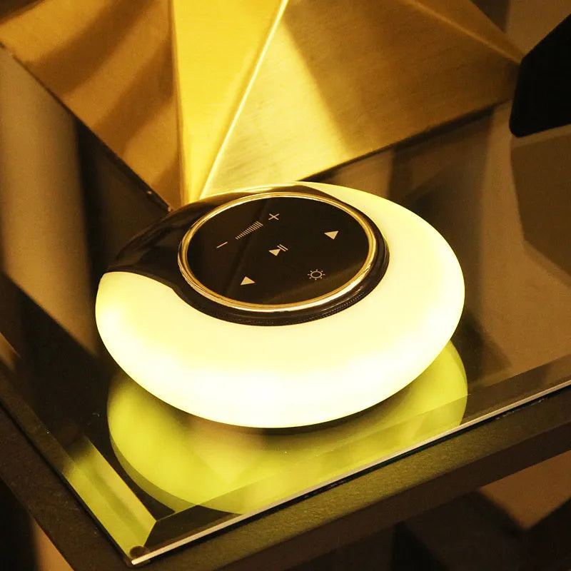 Blue Bluetooth desk lamp with speakers folded on a desk next to a charging cable.