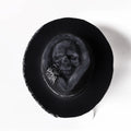 Handmade wool felt skull hat with a conical crown on a model, monochrome print.