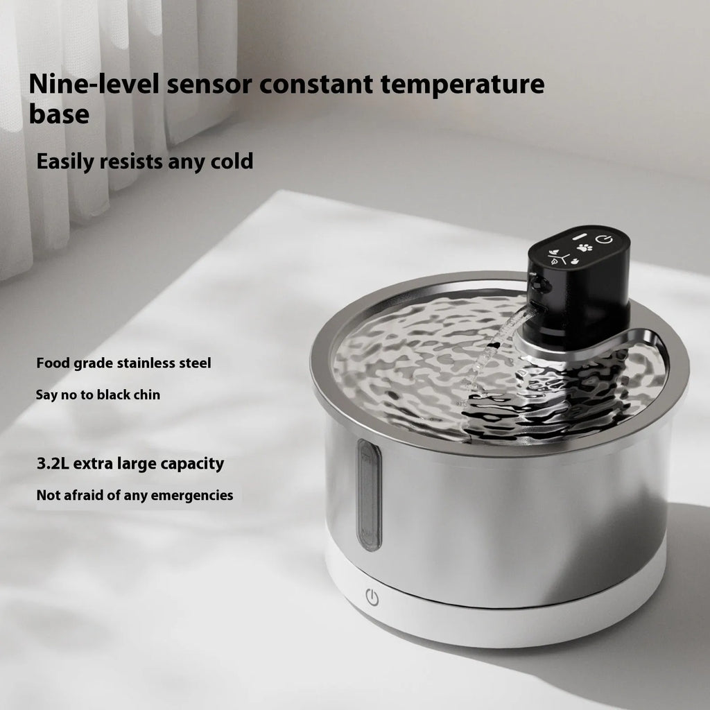 White stainless steel heated pet water fountain on a table with charging cable.