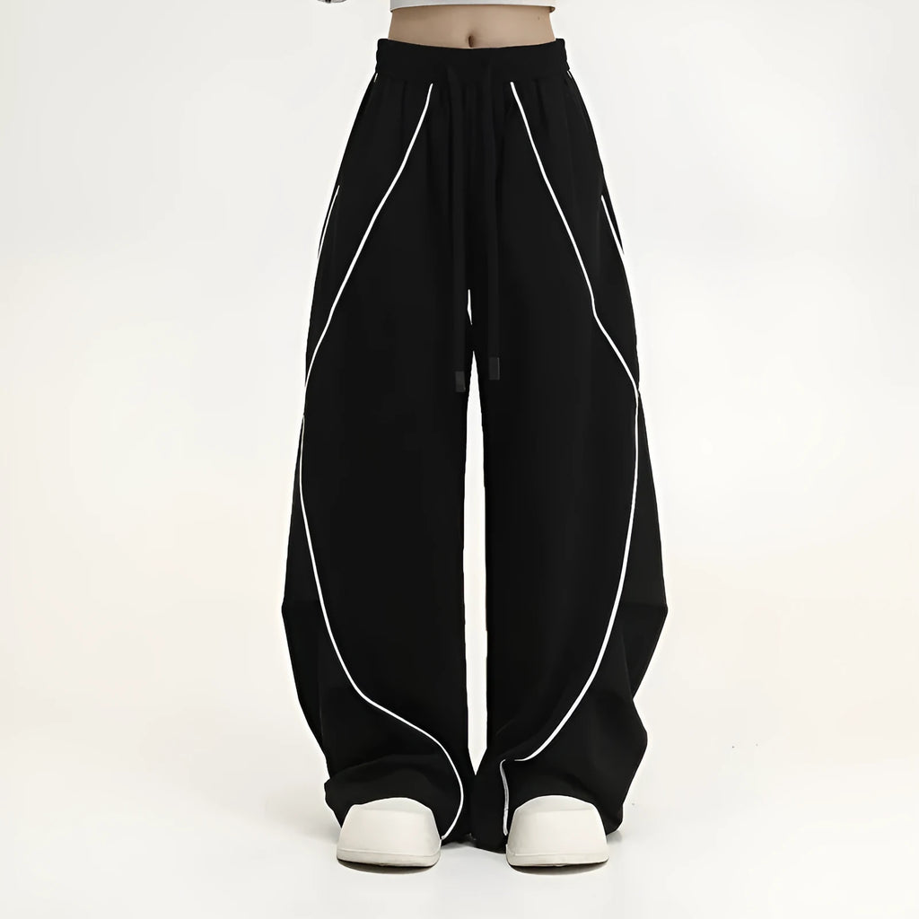 Black trousers with vertical stripes and pleated detail on the legs, showing a loose wide-leg fit.