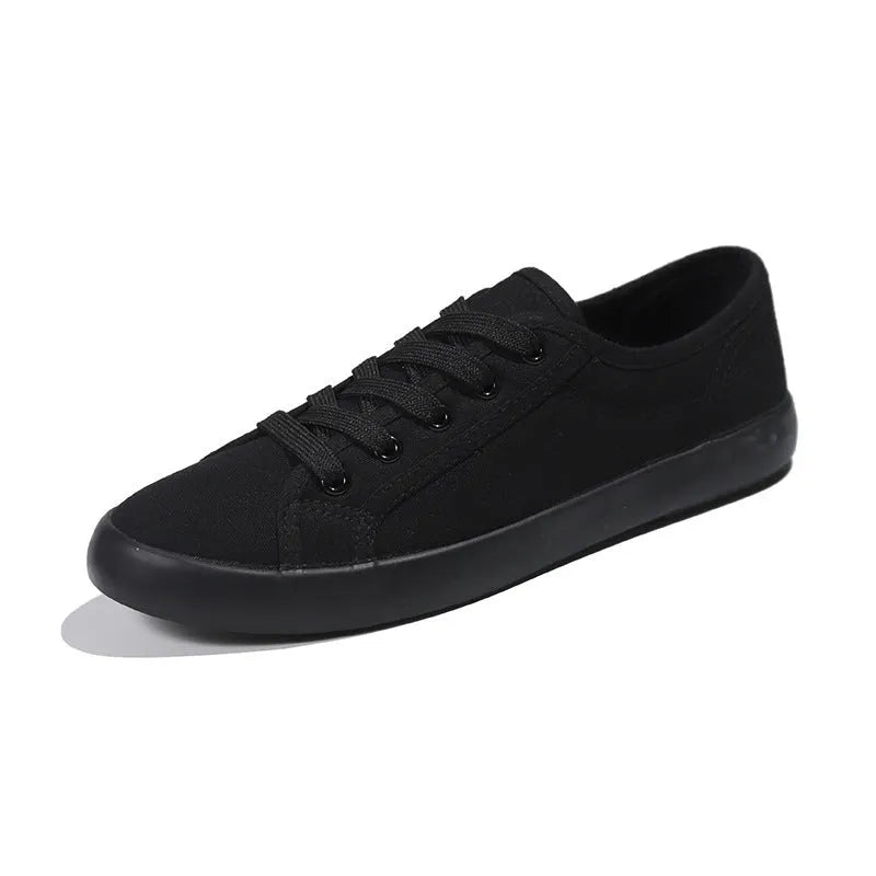 All black canvas low-top lace-up flat shoes for women on a white background