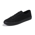 All black canvas low-top lace-up flat shoes for women on a white background