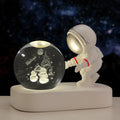 Small clear resin ball night light with glowing astronaut and galaxy scene inside on dark surface