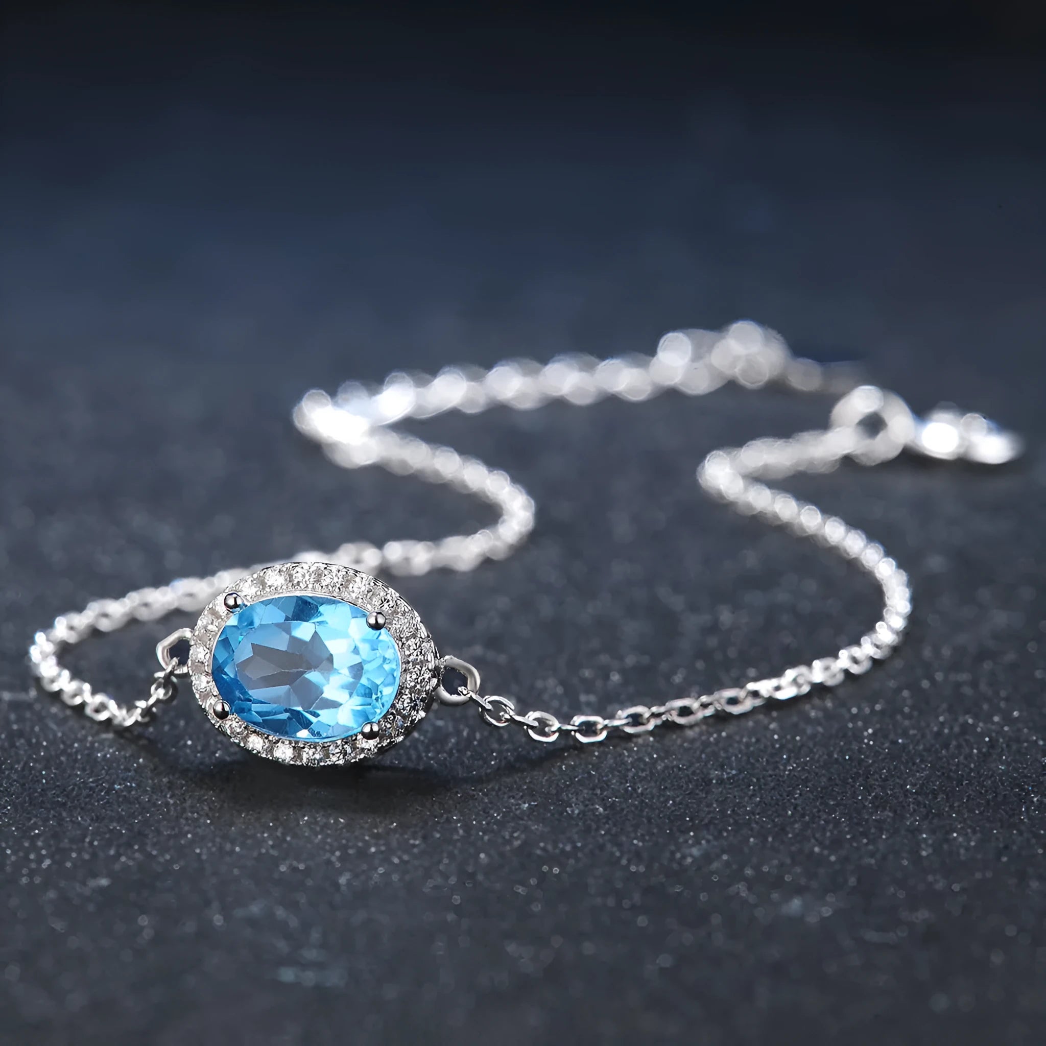 Four-piece sterling silver jewellery set with blue topaz gems showing geometric necklace, earrings, ring, and pendant