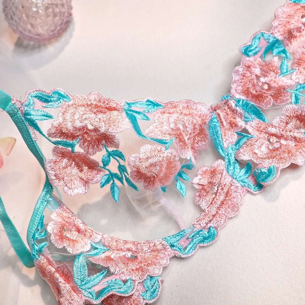 Pink embroidered women's bikini set with a matching mesh pettiskirt laid flat.