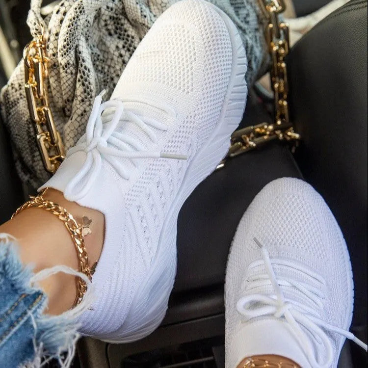 Women's white thick-sole dad-style sports sneakers on a neutral background.
