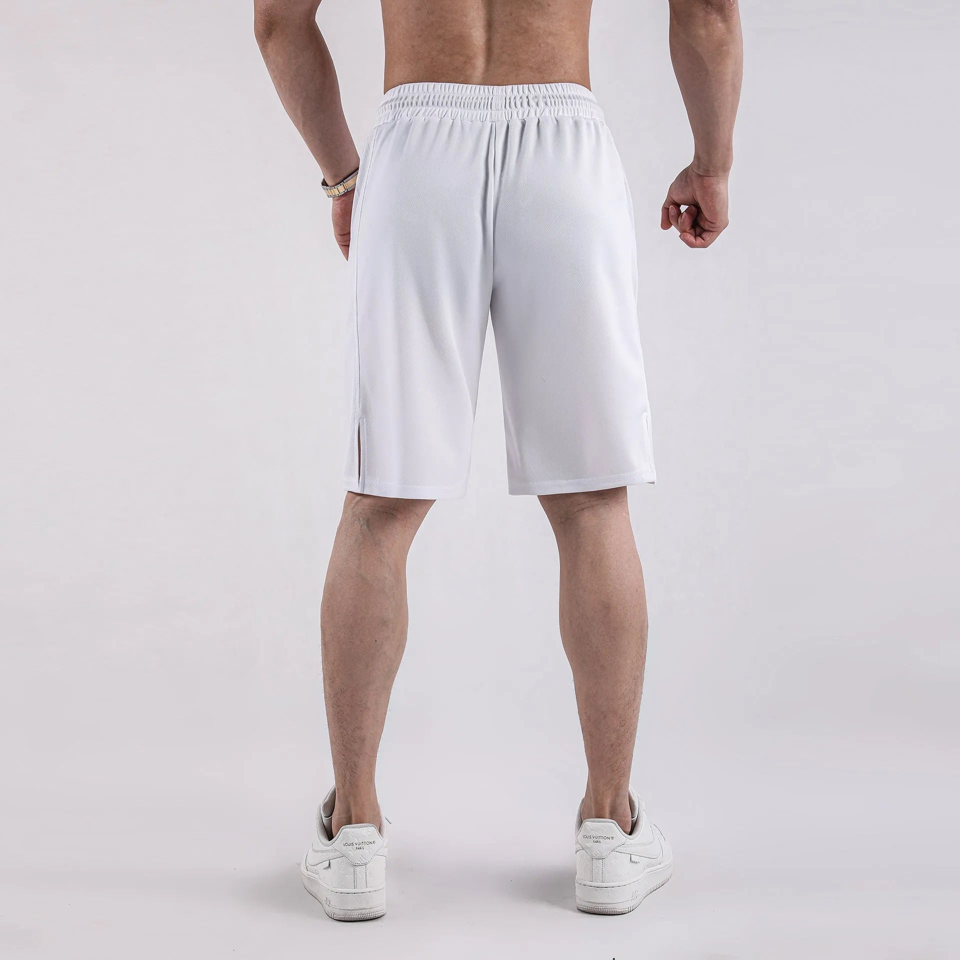 Man wearing black loose-fit mesh capri shorts with an elastic waist for sports.
