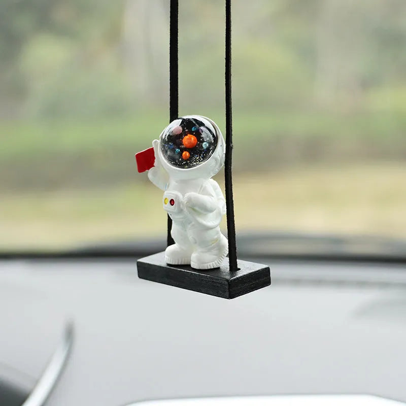 Resin astronaut car pendant showing cartoon astronaut designs including telescope, red flag, and radish variations