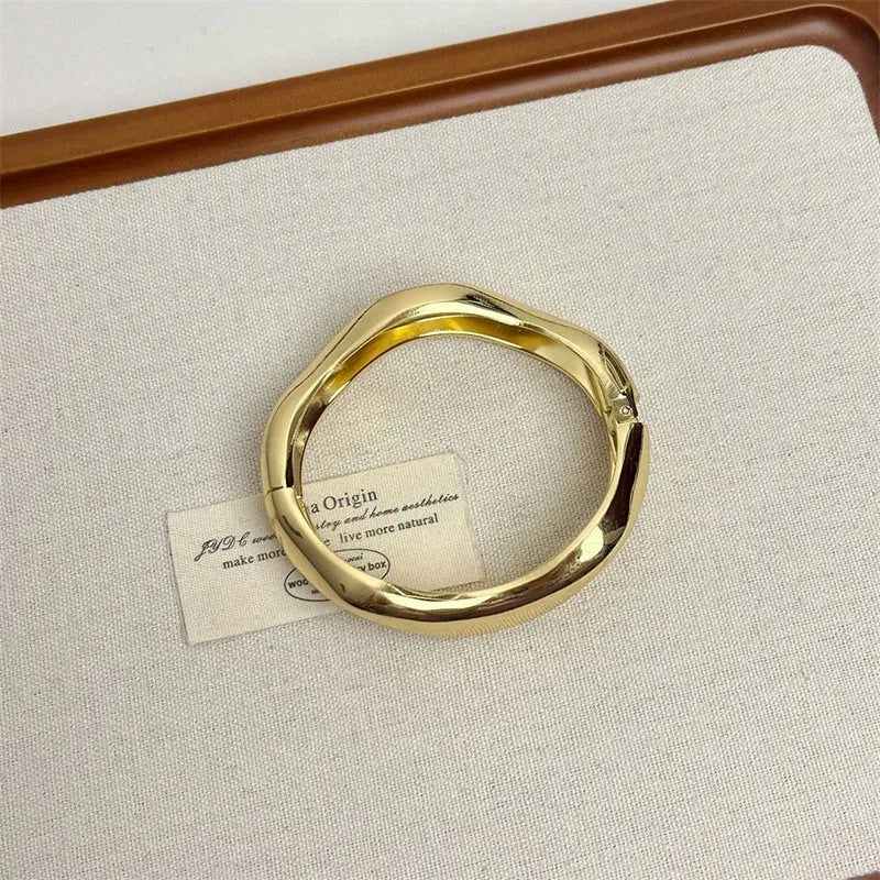 Wide-brimmed irregular zinc alloy bracelet with spring open design and electroplated finish