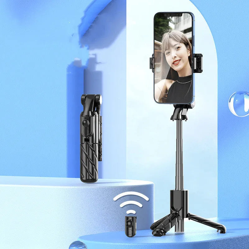 V03 black mini selfie stick Bluetooth tripod extended to 70 cm on a tabletop, phone attached and remote control visible