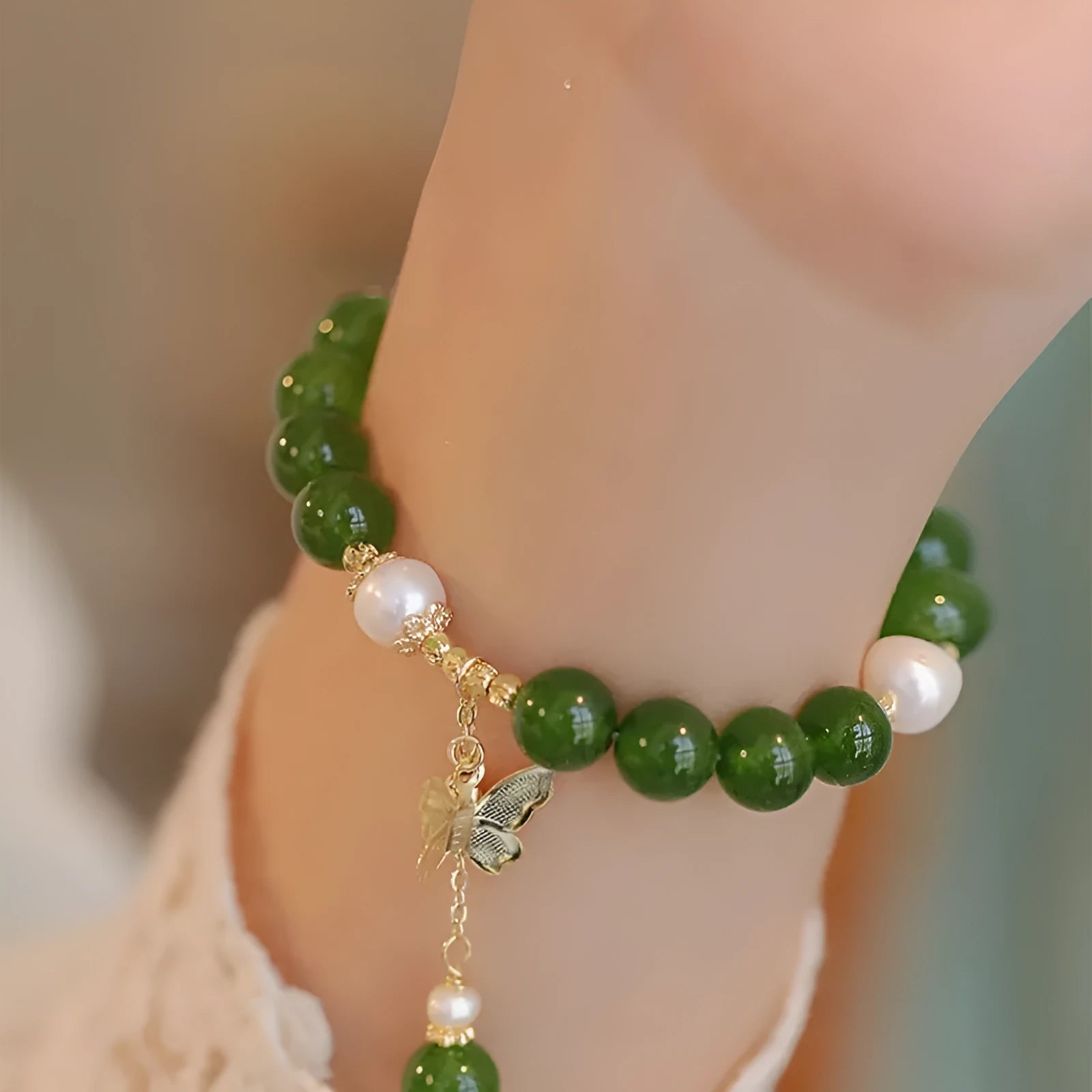 Close-up of a green chalcedony bracelet with round geometric beads on a wrist.