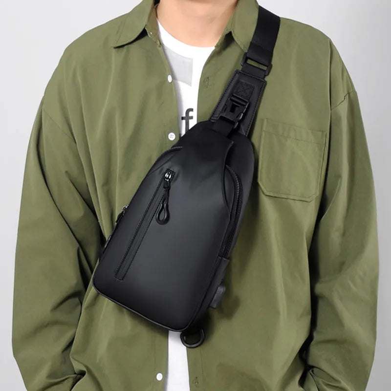 Black sling crossbody chest bag for men with zipper closure and stitched detail on a white background