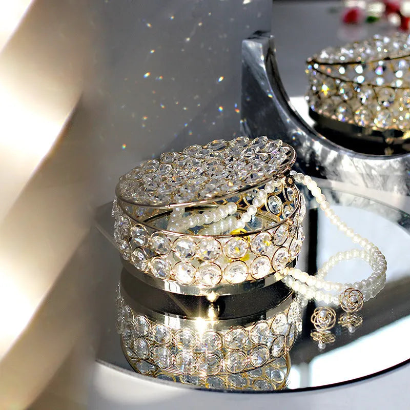 French gold iron jewelry storage box with a clear crystal glass lid on a wooden surface.