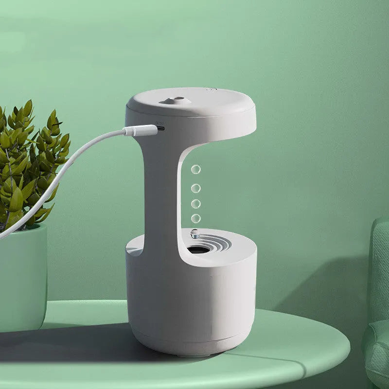 White anti-gravity humidifier with LED clock display emitting mist on a wooden desk.