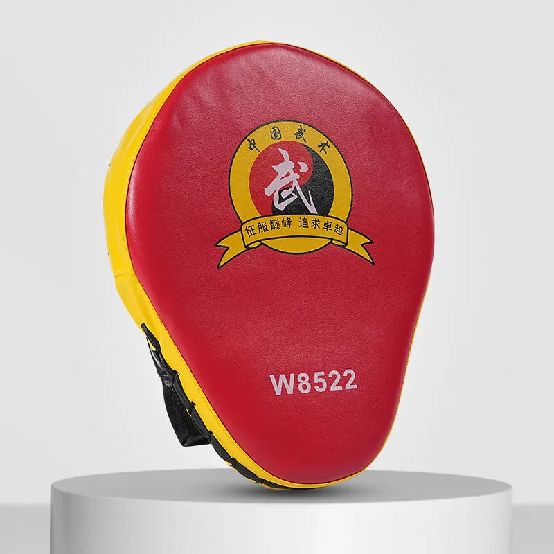 Red and black curved boxing punch mitts held in a trainer's hands for Muay Thai or Sanda practice.