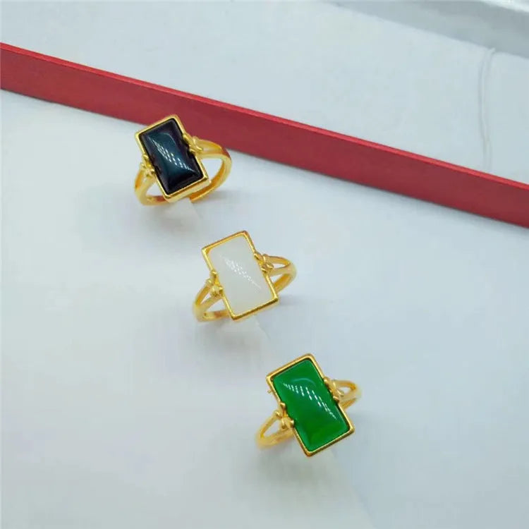A gold-coloured adjustable ring with a large central green artificial gemstone, showing the national style design.