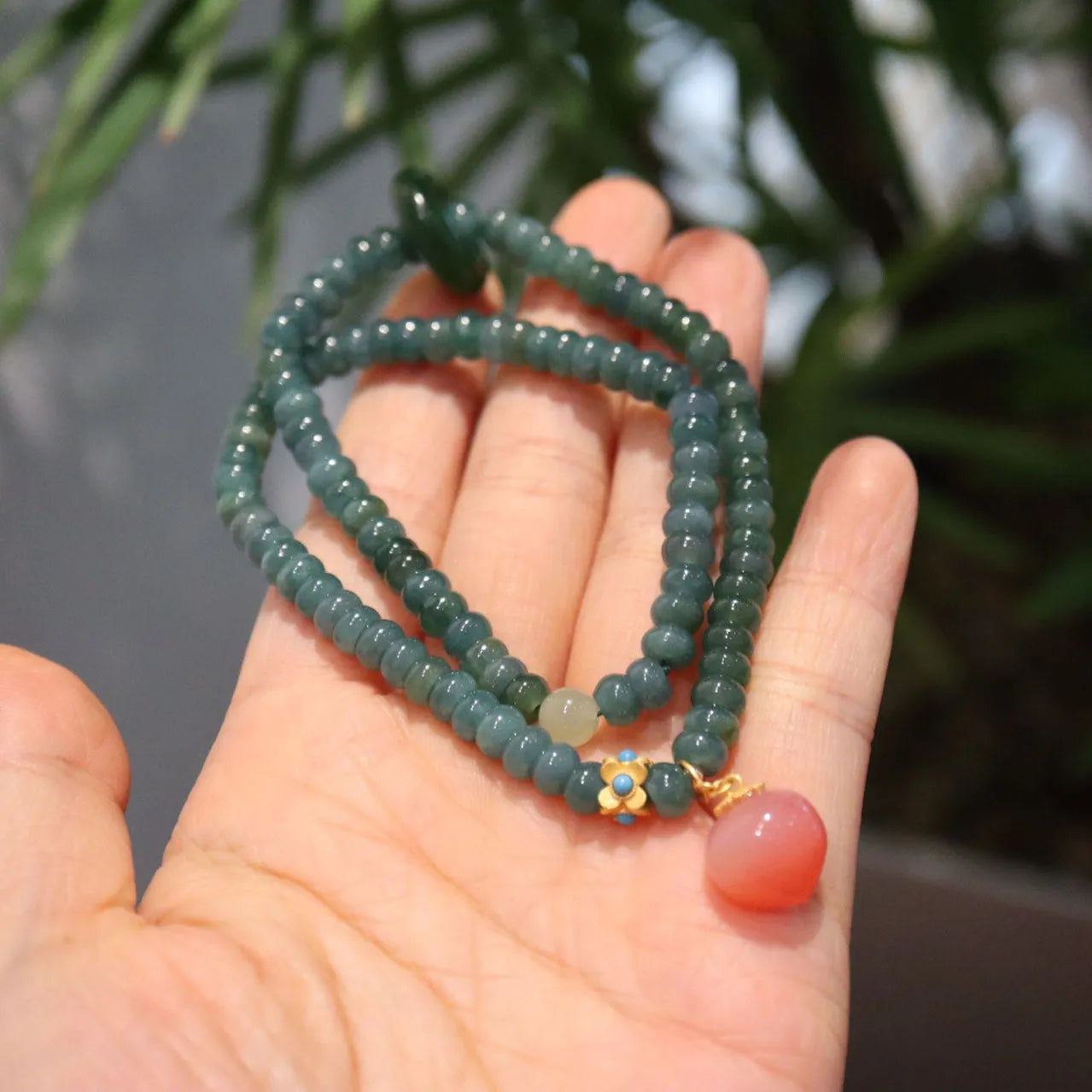 Close-up of a blue water jade and abacus bead bracelet with tourmaline rings and freshwater pearls.