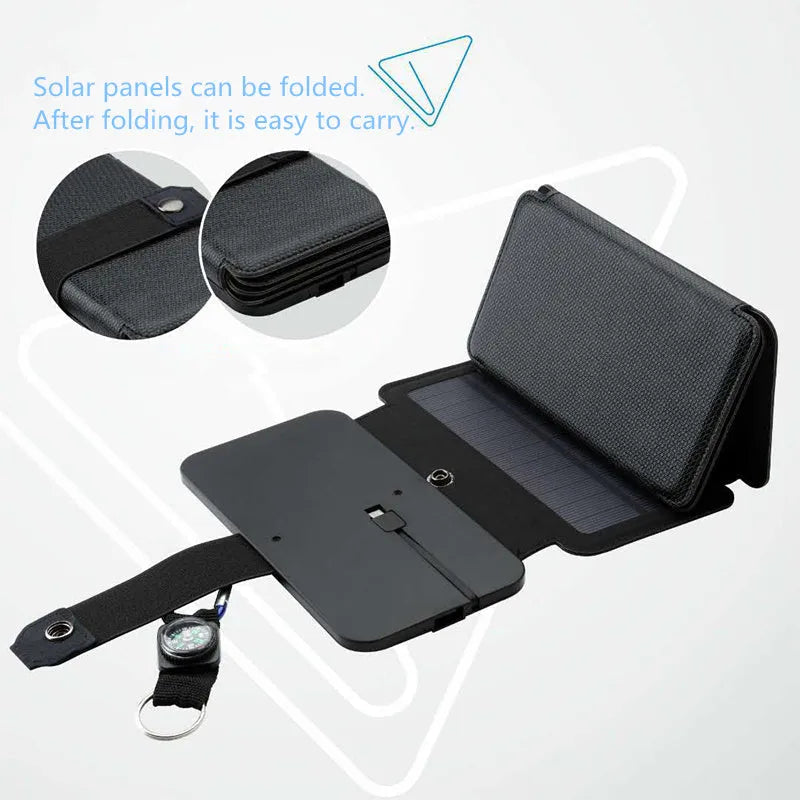 Black folding solar panel charger with monocrystalline cells and USB output, folded flat on a wooden surface, compass buckle visible