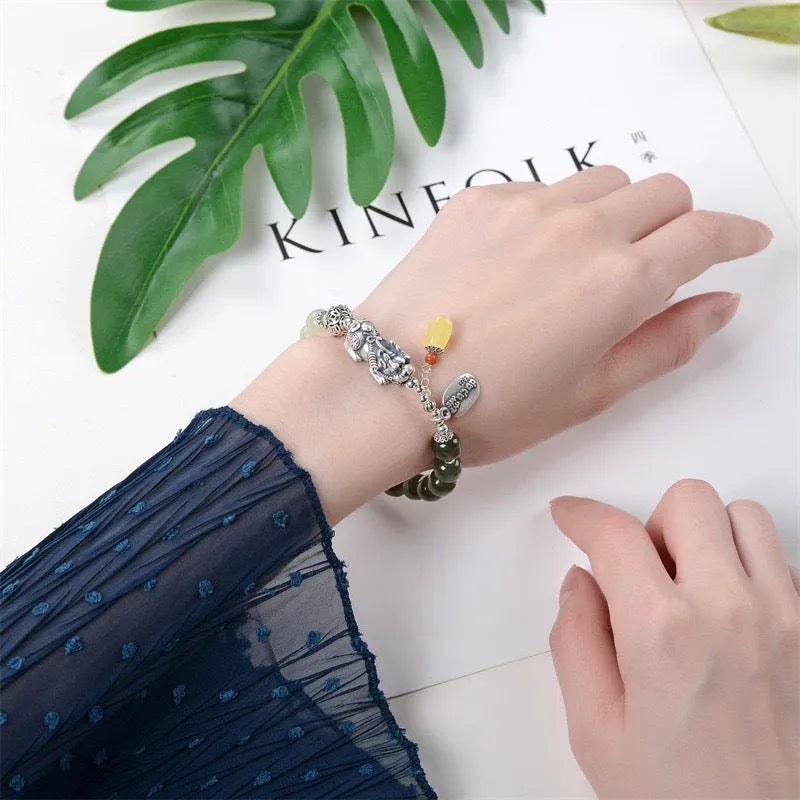 Close-up of a women's silver bracelet with Hetian jade beads and an 8x7mm retro coin charm.
