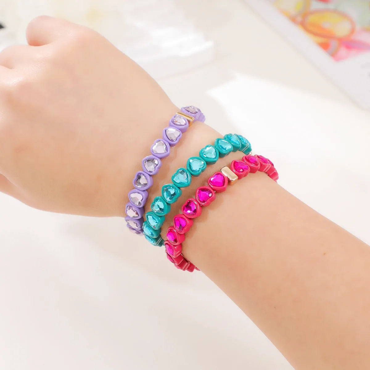 Rainbow coloured alloy heart charms on a stretchy elastic bracelet.