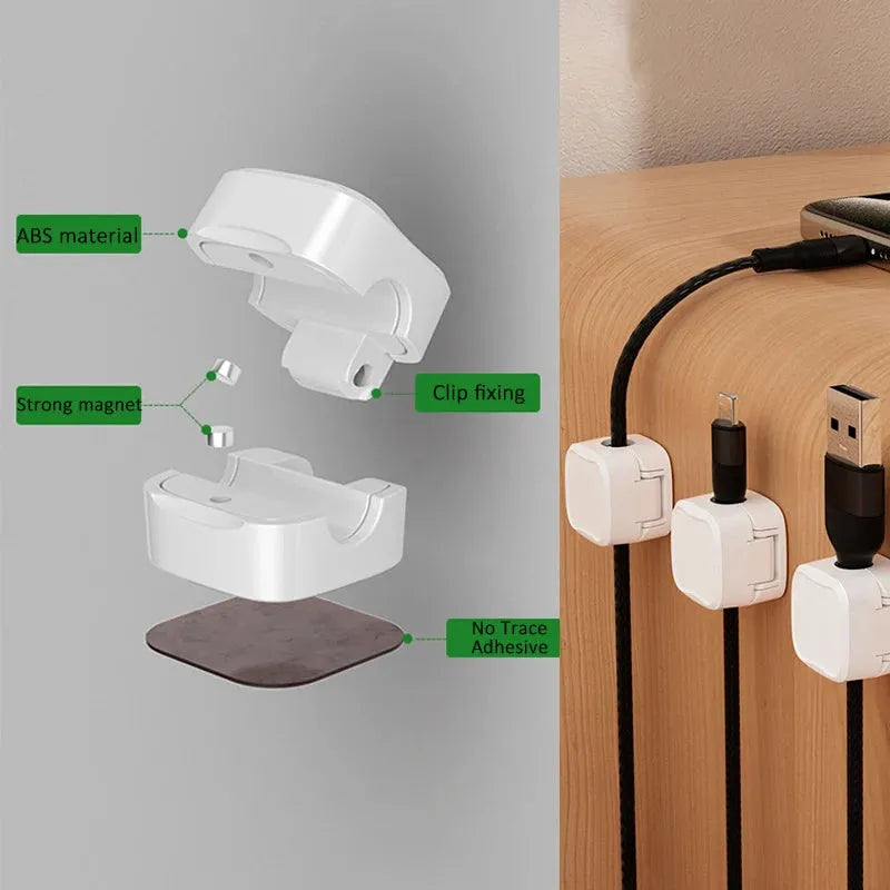 White and black magnetic cable clips holding a USB cable against a wooden desk edge.