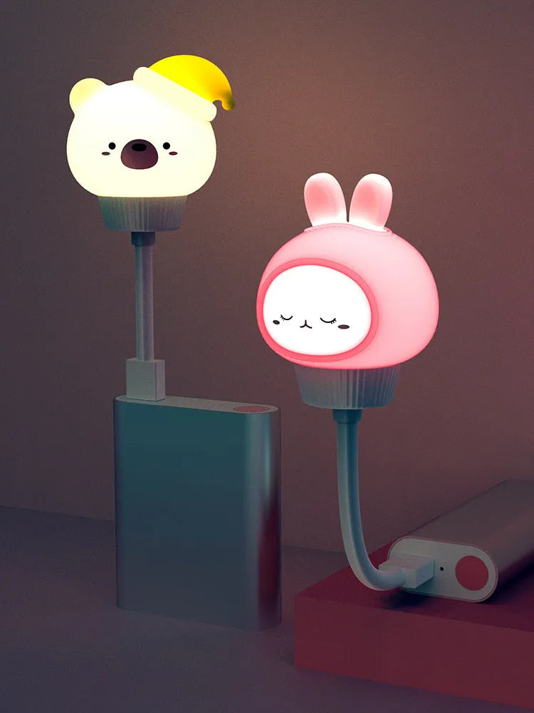 USB portable cartoon animal LED night light with remote control on a bedside table.