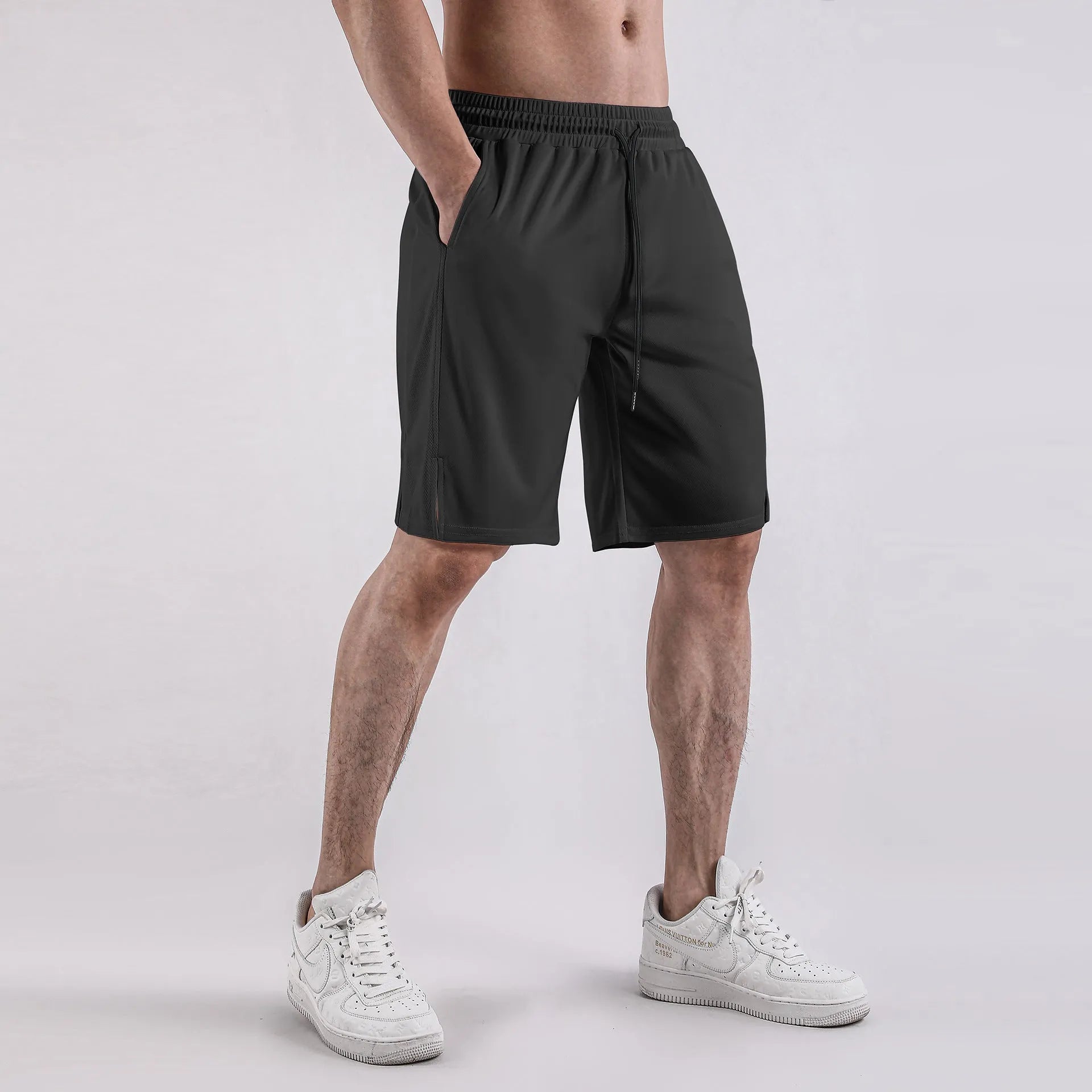 Man wearing black loose-fit mesh capri shorts with an elastic waist for sports.