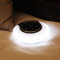 Blue Bluetooth desk lamp with speakers folded on a desk next to a charging cable.
