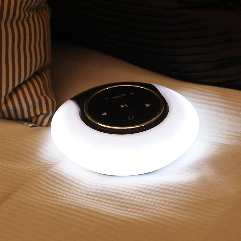 Blue Bluetooth desk lamp with speakers folded on a desk next to a charging cable.