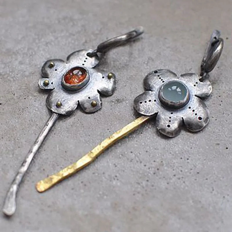 A pair of long retro-style earrings with a geometric floral shape in an asymmetric two-tone colour finish.