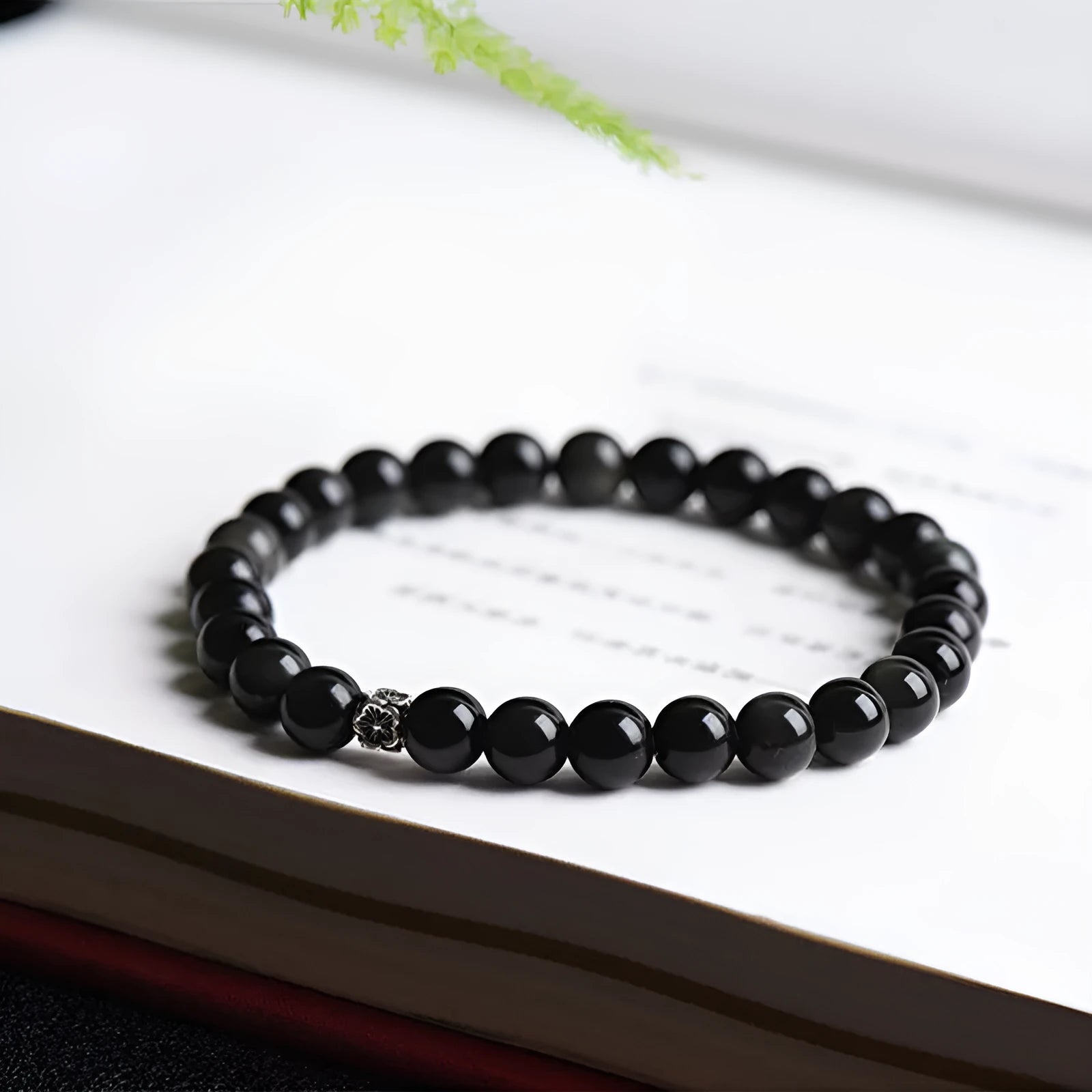 Natural obsidian bracelet with S925 sterling silver flower accessories on a wrist