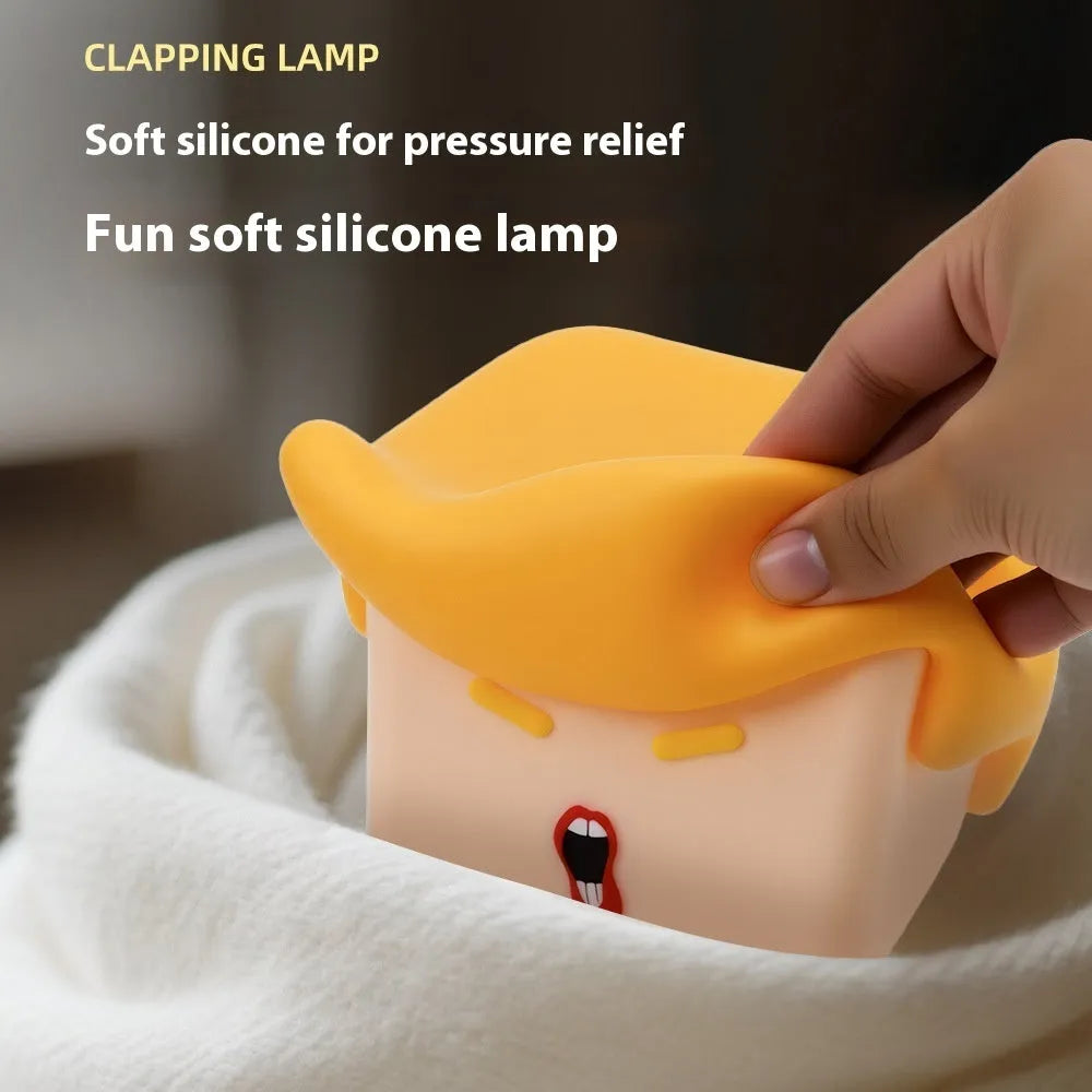 Yellow soft silicone pat lamp with USB charging port on a wooden table showing night light glow