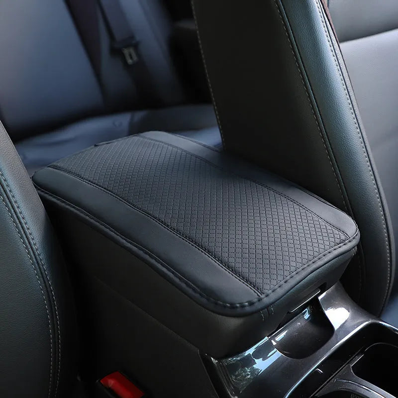 Embossed fibre leather car armrest box cushion measuring 32cm by 19cm in black with red trim