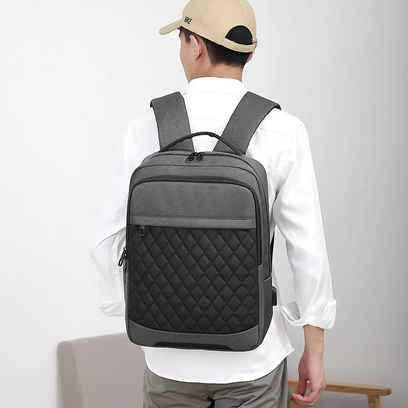 Men's solid colour Oxford cloth backpack with curved shoulder strap in black, blue, or grey.