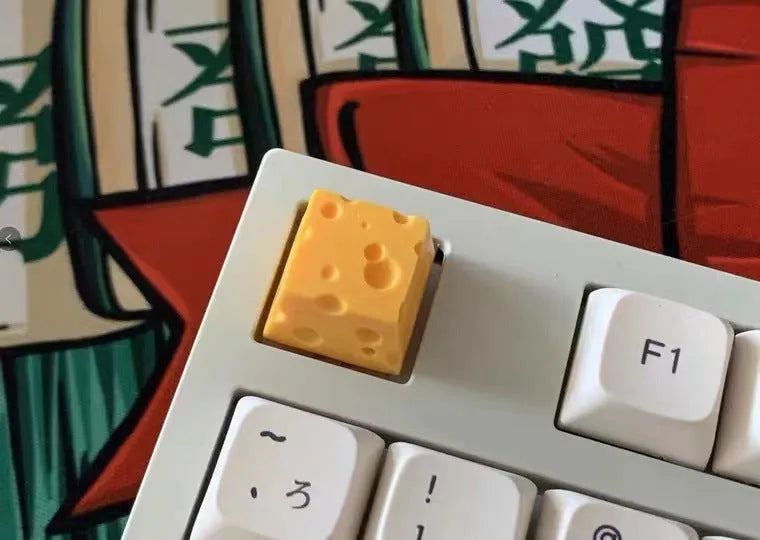 Close-up of a bright yellow resin key cap with a detailed sculpted cheese design.