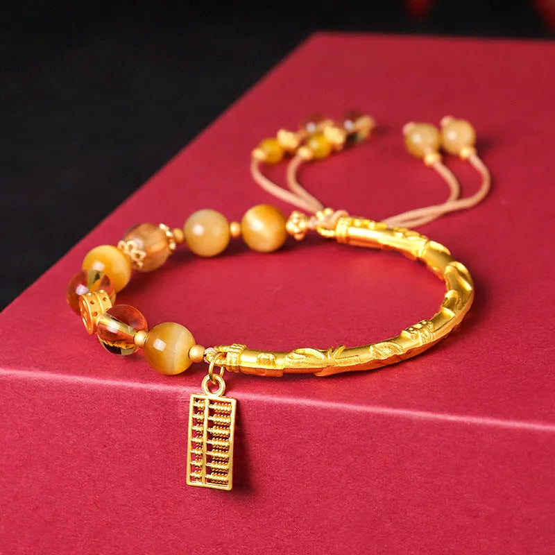 Close-up of handmade abacus bracelet with tigereye, citrine, and yellow tower crystal beads in a diamond shape on a wrist.