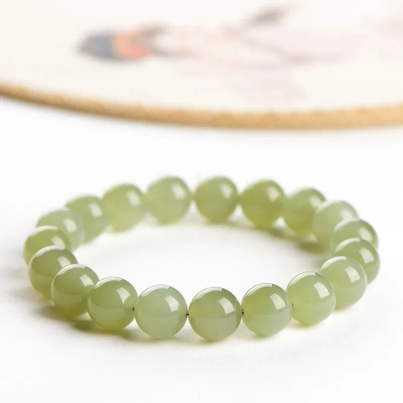 Polished Hetian jade ball bracelet showing different bead sizes on a wrist, in clear ice-like colours.