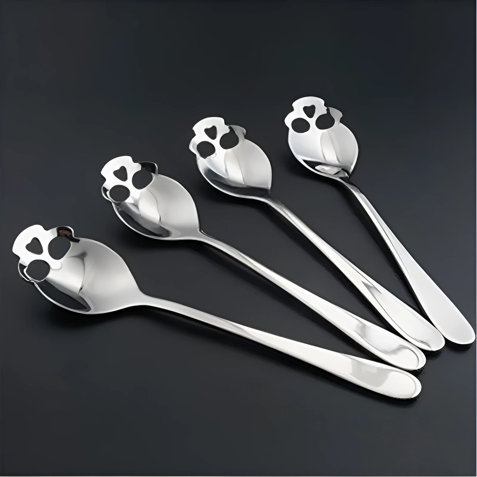 Stainless steel skull-shaped coffee mixing spoon on a dark surface