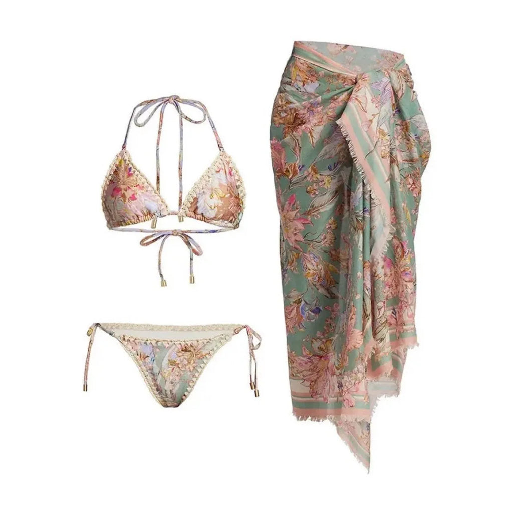 Women's creamy-white floral bikini swimsuit set with matching skirt on beach