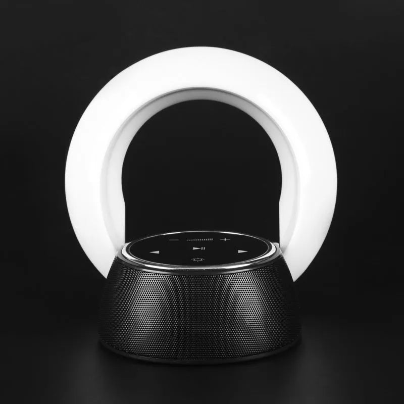 Blue Bluetooth desk lamp with speakers folded on a desk next to a charging cable.
