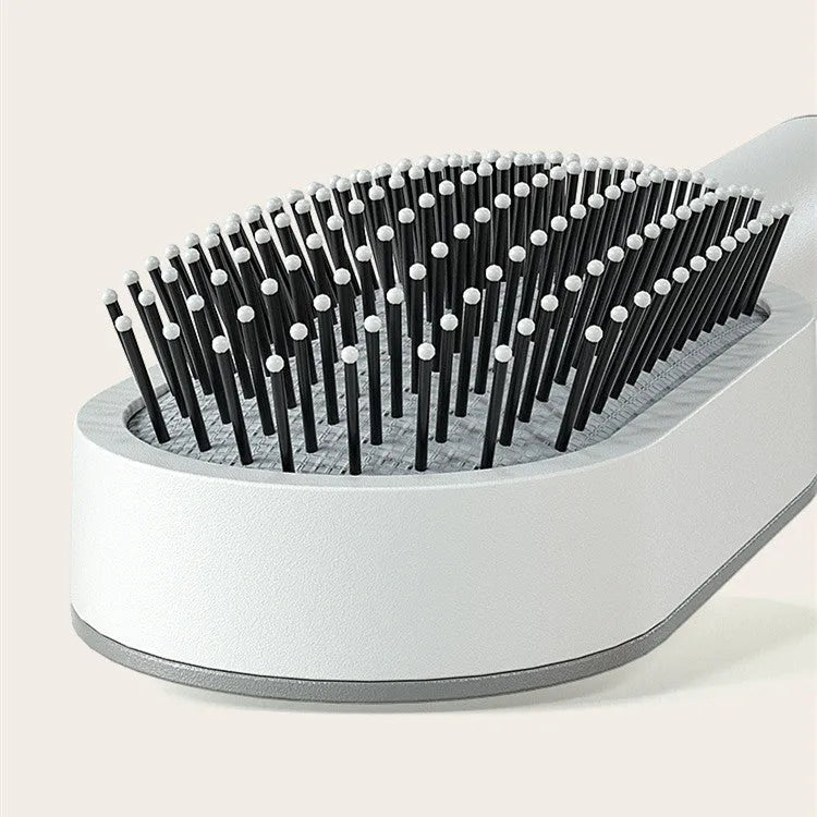 Self-cleaning air cushion hair brush in white, black gold, or black purple with ergonomic handle