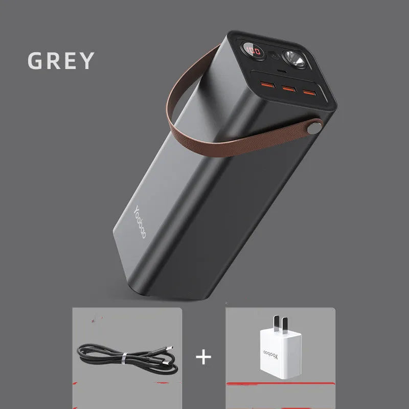 Black portable power bank with digital display, 220V socket, and USB ports on a wooden table.