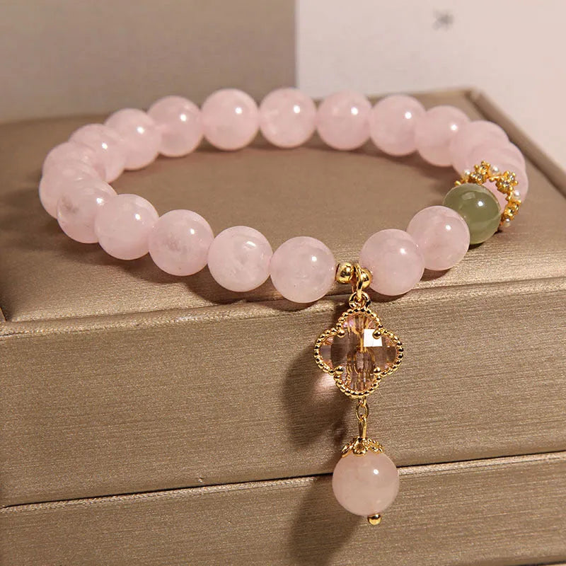 Pink women's bracelet with a crystal four-leaf clover pendant and rhinestone details on an adjustable chain.