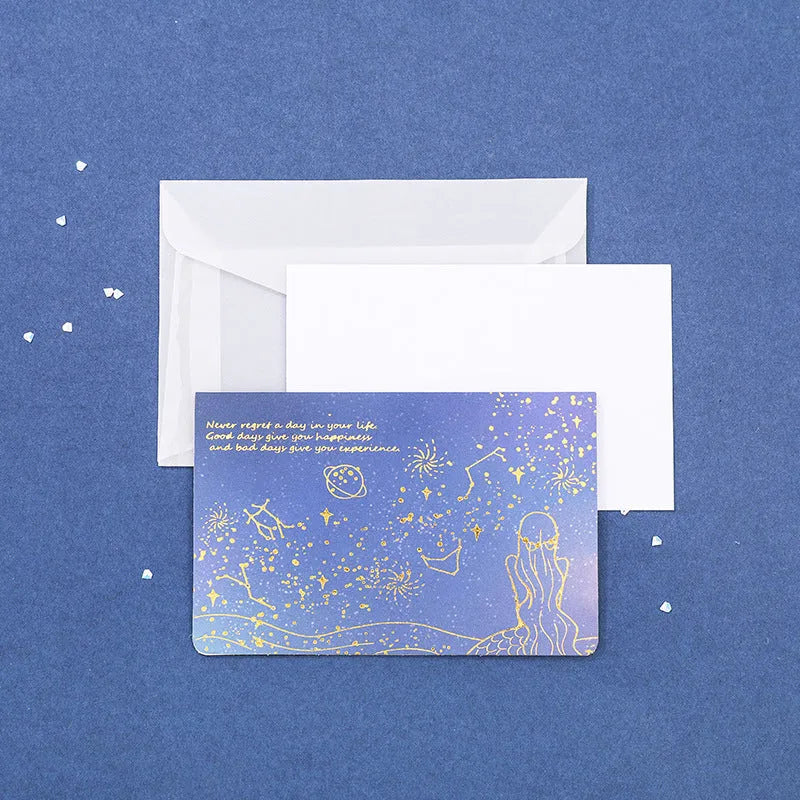Set of three gilded greeting card envelopes in galaxy colour designs on a dark background.