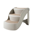 Foldable grey plastic pet stairs with non-slip mat placed next to a sofa for a small dog.
